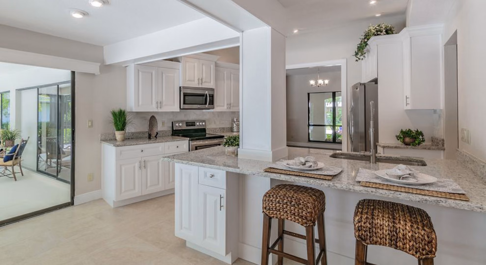 Kitchen: white raised-panel with wicker stools and sunroom