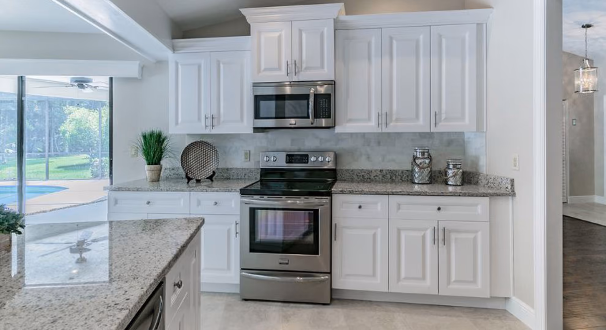 White raised-panel kitchen with a pool view