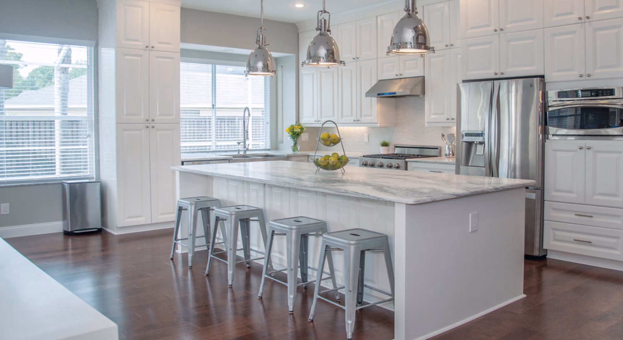 Kitchen: white island with metal stools and stainless appliances