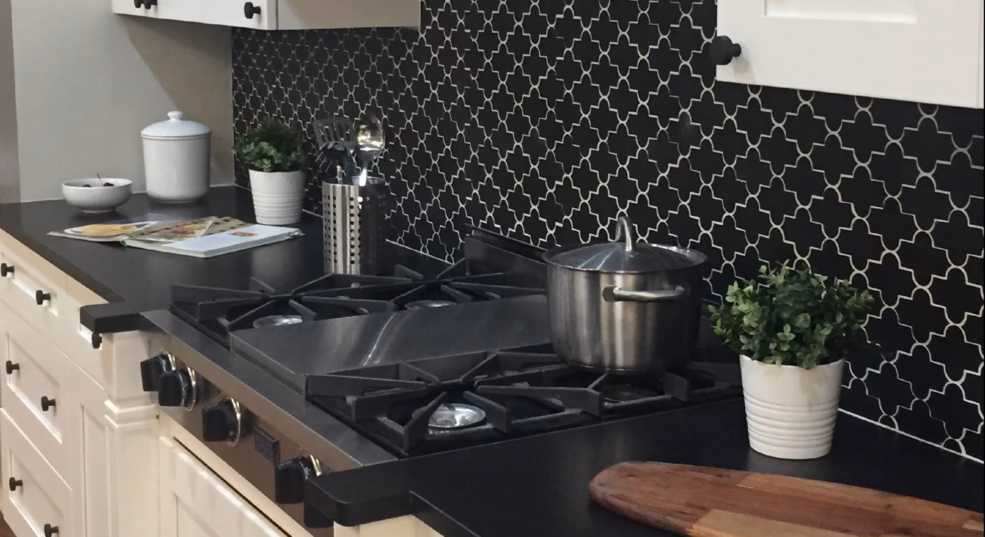 Kitchen close-up: white cabinets with black cooktop and black tile backsplash