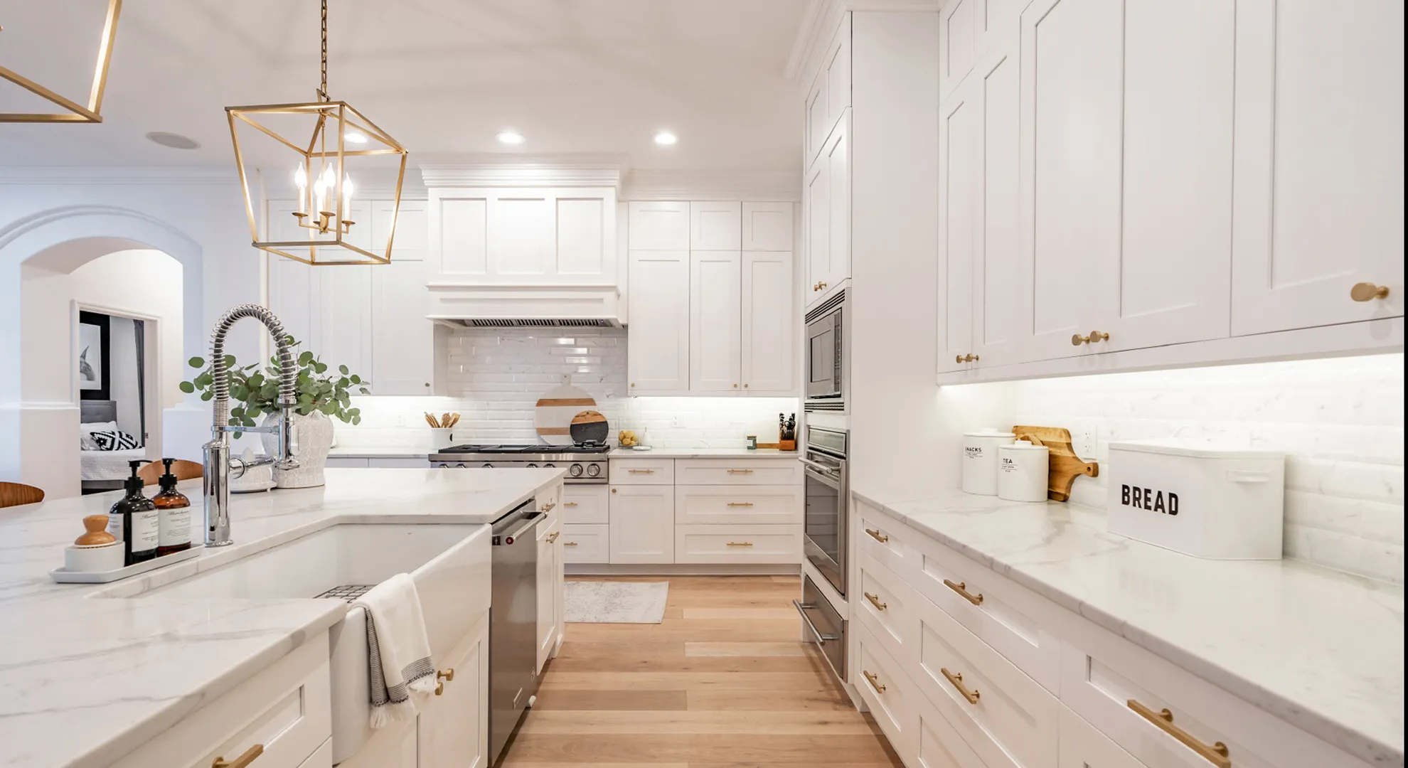 White EliteCraft shaker kitchen with brass pendants and a farmhouse sink