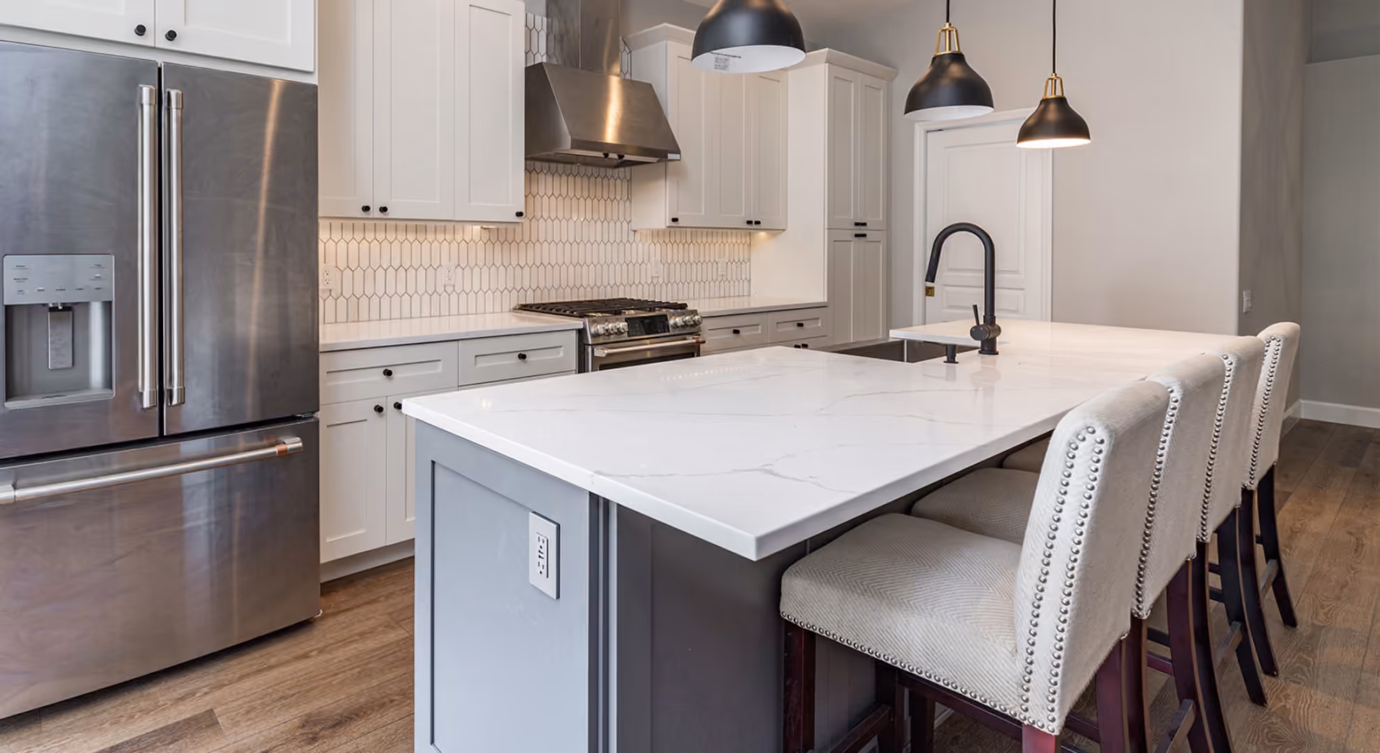 Gray island kitchen with white stools